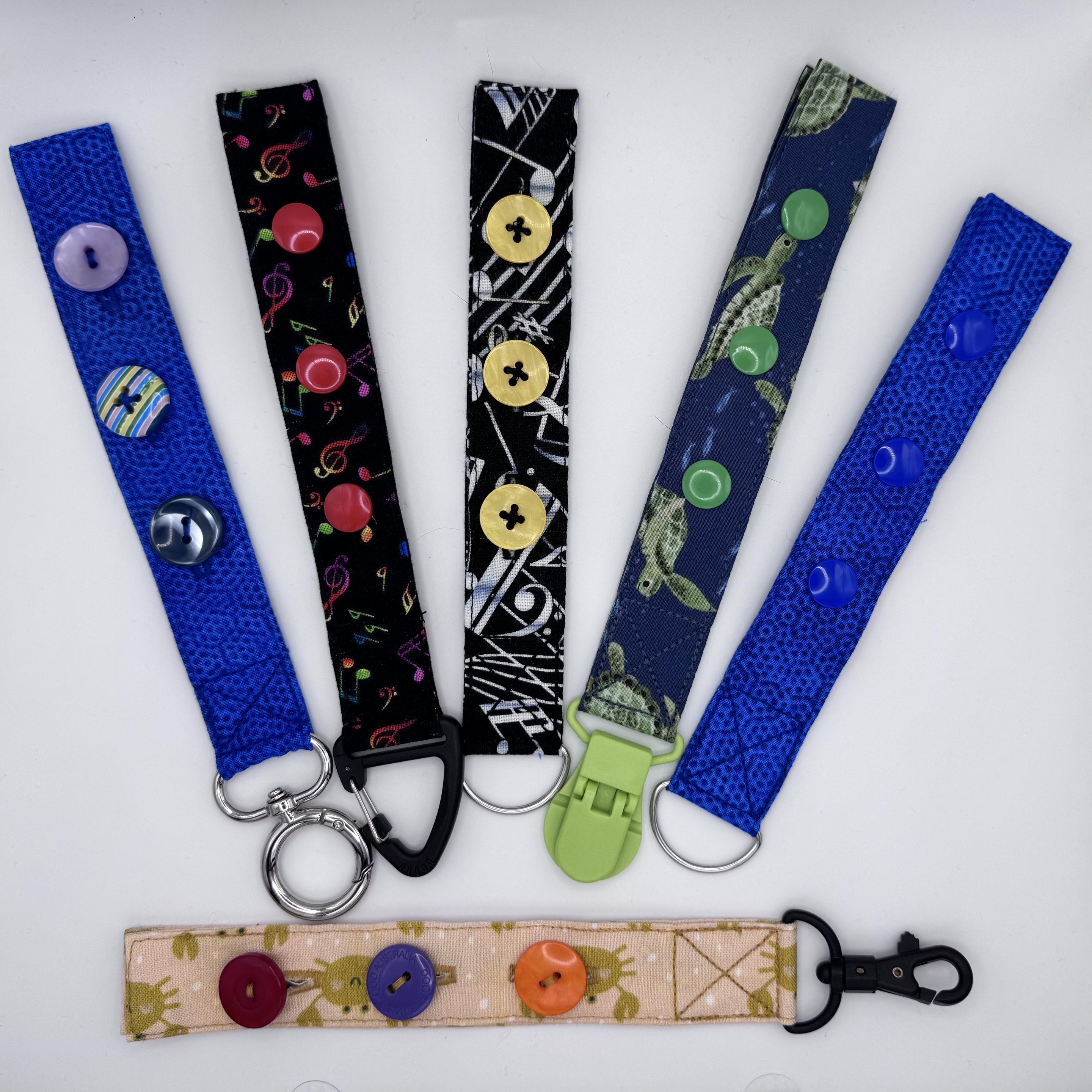 A collection of six fidget toys made from different fabrics. Some have buttons and buttonholes, some have poppers